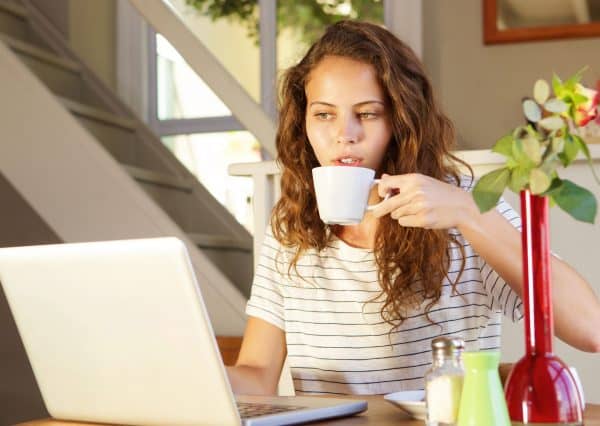 Portrait of a young woman working on laptop at home with coffee picture